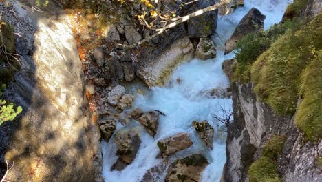 Small-torrential-river-leads-through-rocky-canyon-on-the-Karwendelsteg-hiking-trail-in-the-near-of-Scharnitz-in-Austria,-tilt-shot-close-up