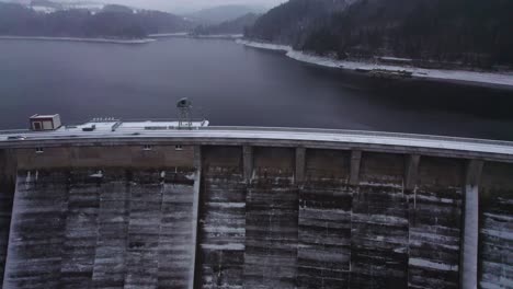 Aerial-tilt-up-view-of-the-reservoir-from-over-the-concrete-arch-dam-covered-with-thick-layer-of-snow