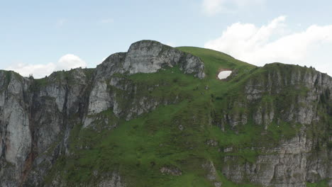 Er-Fliegt-Auf-Eine-Wunderschöne-Felsformation-In-Der-Schweiz-Zu-Und-über-Sie-Hinweg-Und-Enthüllt-Ein-Atemberaubendes,-Tiefgrünes-Tal