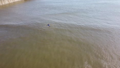 Hombre-Nadando-En-Un-Océano-Frío-Mientras-Usa-Un-Sombrero-Y-Guantes