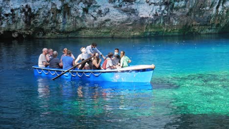 Barquero-Y-Turistas-En-Barco-Con-Máscara-Recorriendo-El-Hermoso-Lago-Y-Cueva-Melissani-En-Kefalonia,-Grecia