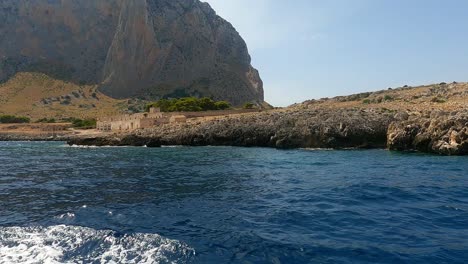 Typical-old-Sicilian-seafront-Tonnara-Del-Secco-used-for-tuna-fishing-as-seen-from-boat-in-Sicily