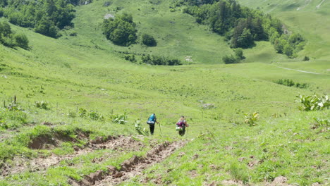 Following-two-hikers-walking-downhill-in-a-beautiful-Swiss-landscape