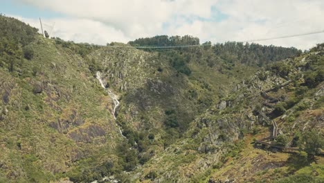 Luftaufnahmen-Von-Drohnen,-Die-Bei-Sommersonne-In-Portugal-Zur-Huge-Brücke-Und-Zum-Wasserfall-Mitten-In-Einem-Dschungelwald-Führen