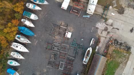 Small-shipyard-with-boat-parts-and-finished-boats,-aerial-top-down-view