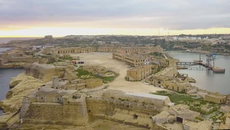 Aerial-footage-of-the-medieval-Fort-Ricasoli-and-the-lighthouse-from-Malta's-Grand-Harbour