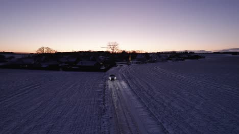 Drohnenansicht-Eines-Autos,-Das-Auf-Einer-Verschneiten-Straße-In-Der-Skandinavischen-Winterlandschaft-Fährt-–-Dolly-Aufnahme