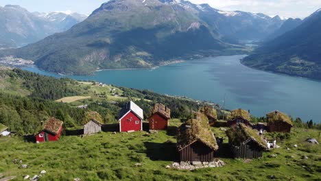 Raksetra-Loen---descending-aerial-approaching-cabins-with-magnificent-view-over-fjord-and-Olden---Norway-at-summer-sunny-day-with-tourists-walking-around