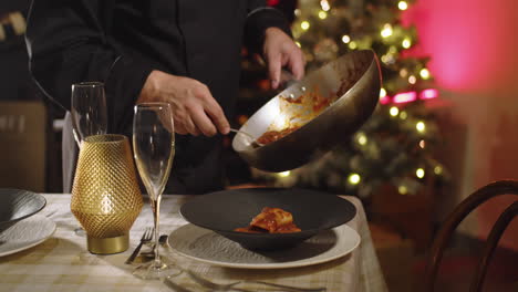 Close-up-shot-of-unrecognizable-chef-serving-gourmet-pasta-in-a-holiday-scene-with-a-blurred-christmas-tree