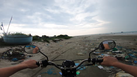 Riding-motorbike-on-beach-with-garbage-in-cloudy-day