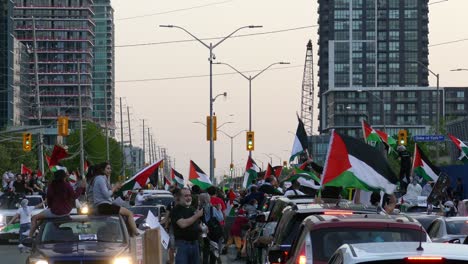 A-crowd-of-protesters-at-the-Free-Palestine-rally-on-the-road,-cars,-and-people-occupied-the-road