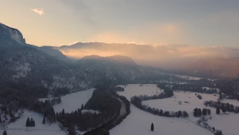 Drone-shot-of-a-mysterious-landscape-at-sunset-in-the-mountains-covered-with-clouds-in-wintertime