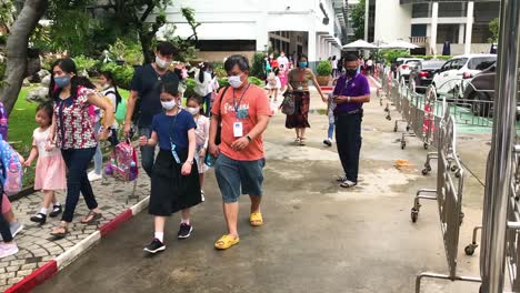 Asian-Parents-picking-up-little-students-after-school-in-the-evening,-all-people-wearing-medical-masks