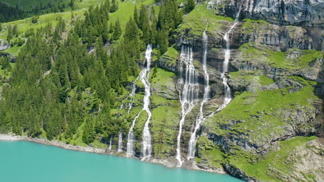 Cinematic-aerial-of-multiple-waterfalls-streaming-from-mountain-into-blue-lake