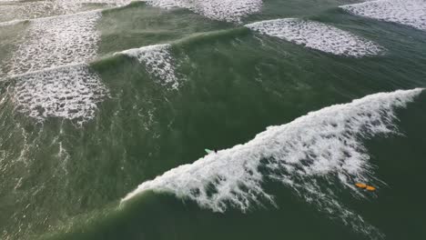 Aerial-view-of-surfer-riding-wave-on-tropical-beach