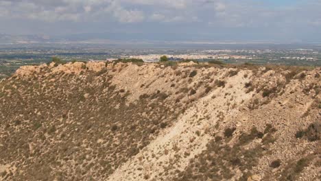 Drone-Flying-Over-Dry-Desert-Hillside-To-Reveal-Green-Spanish-Countryside-Farm-Fields