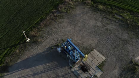 Aerial-View-Of-An-Oil-Pumpjack-Operating-In-The-Oilfield-Near-Ploiesti,-Romania-At-Daytime
