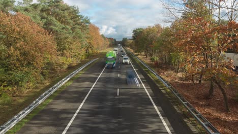 Traffic-In-Daylight-At-The-A28-Highway-In-Gelderland,-the-Netherlands-With-Autumnal-Trees
