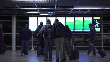 Gente-Mirando-El-Monitor-De-Horarios-Dentro-De-La-Terminal-Del-Aeropuerto-De-Schiphol-En-Holanda