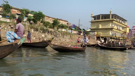 Einheimische-Mit-Ihren-Einzigartigen-Bootstaxis-Rudern-Am-Ufer-Des-Buriganga-Flusses-In-Dhaka-Vorbei