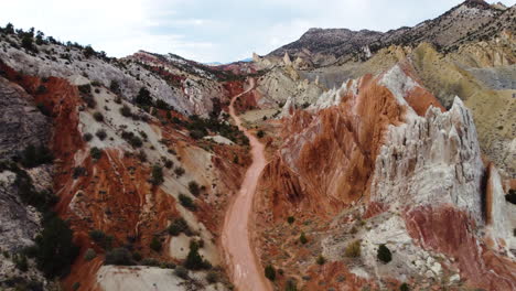 A-road-in-a-narrow-valley-in-a-mountainous-massif-with-ochre-colors,-slow-motion,-unique-red-rock-formations-in-Utah