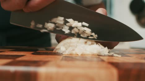 Slicing-onion-with-big-kitchen-knife-on-wooden-cut-board