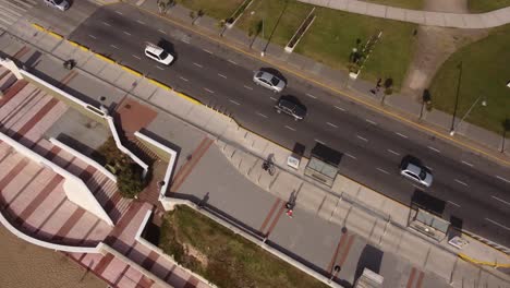 Beautiful-top-down-view-of-a-cyclist-on-the-street-of-Mar-del-Plata-at-Argentina-on-a-sunny-day-with-cars-moving-on-the-road