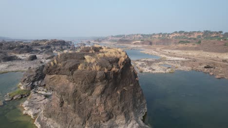 Aerial-panning-moving-forward-shot-of-water-and-big-rocks-in-India