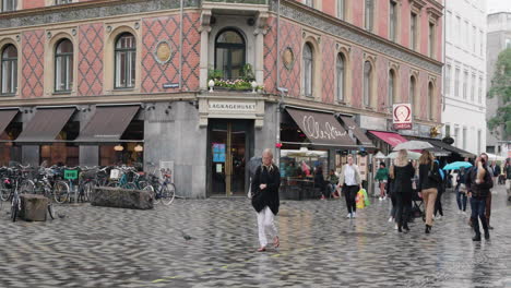 Gente-Con-Paraguas-Pasando-Por-Una-Panadería-En-Copenhague,-Dinamarca-En-Un-Día-Lluvioso