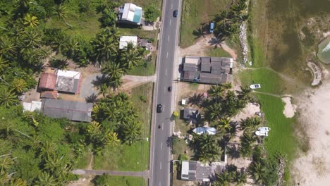 Drone-shot-following-a-car-and-motorbike-along-road-on-sunny-day-in-Sri-Lanka
