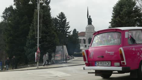 Convoy-of-Eastern-European-Trabant-retro-classic-cars-drive-through-city-streets,-next-to-Mother-Bulgaria