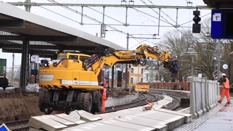 Workers-at-maintenance-site-and-construction-work-on-train-tracks-in-Zutphen-with-heavy-machinery-putting-large-blocks-in-its-place