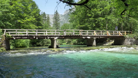 Un-Viejo-Puente-De-Madera-En-Eslovenia-Cruzando-El-Río-Con-Agua-Clara-Y-Hermosos-Colores