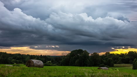 Dark-clouds-flying-over-agricultural-field-during-yellow-sunlight-hiding-at-horizon---time-lapse-shot