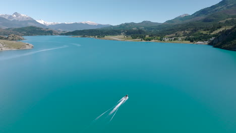 Aerial-Flying-Over-Smooth-Turquoise-Lake-General-Carrera-With-Speedboat-Travelling-Past