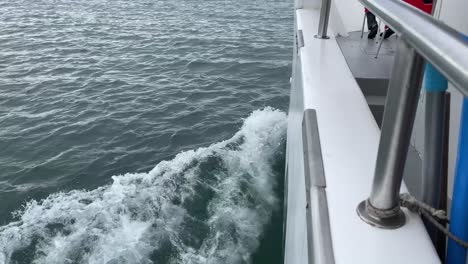 Barco-Blanco-Navegando-En-El-Agua-Del-Océano-Provocando-Una-Estela,-Vista-Desde-El-Costado-Del-Barco