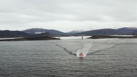 Boat-Cruising-At-Norwegian-Sea-With-Storseisundet-Bridge-In-Background-In-Norway
