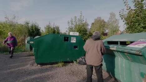 Elderly-Couple-Throws-Trash-at-Recycle-Station,-Wide-Shot-Tracking-to-Right