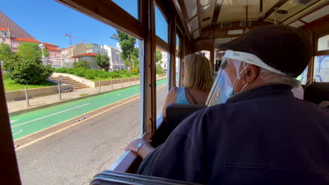 Tourists-Sightseeing-Lisbon-Street's-Architecture-Through-Opened-Windows-of-Vintage-Tram-Tour-Daytime-when-Car-Passing-by