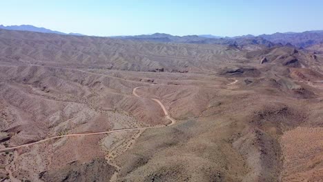 Aerial-drone-view-overlooking-traffic-on-a-desert-road,-in-sunny-Kingman-wash,-USA
