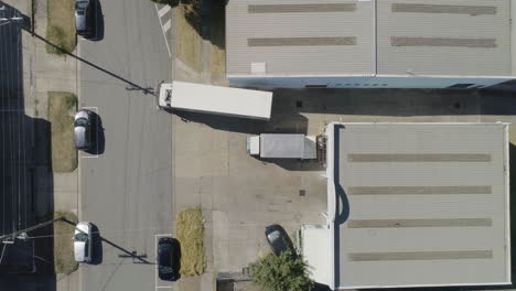 White-truck-and-carry-haul-leaving-depot-from-aerial-perspective-on-summers-day