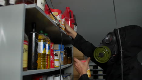 A-prepper-wearing-a-gas-mask-in-a-nuclear-fallout-bunker-stockpiling-food