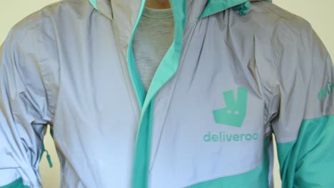 Food-courier-zipping-Deliveroo-jacket