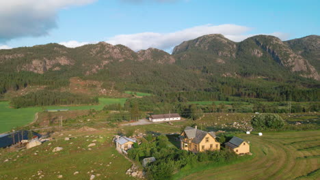 Traditional-Norwegian-Houses-In-Countryside-In-Ryfylke,-Rogaland,-Norway-With-Rocky-Mountainous-Landscape-In-Background