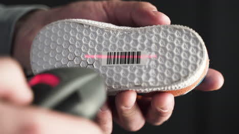Closeup-of-a-man-scanning-a-barcode-on-a-kids-shoe-sole-with-laser