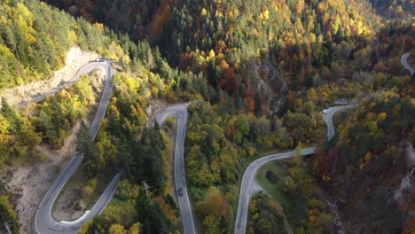 Aerial-footage-over-pyrenees-cars-driving-down-mountain-high-pass-forest-in-autumn-in-north-Spain-during-beautiful-sunset