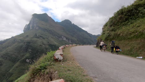 Dos-Amigos-Vietnamitas-Dando-La-Vuelta-En-Sus-Bicicletas-En-La-Carretera-De-Montaña-Del-Pavimento