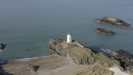 An-aerial-view-of-Twr-Mawr-Lighthouse-on-Ynys-Llanddwyn-island,-flying-right-to-left-around-the-lighthouse,-Anglesey,-North-Wales,-UK