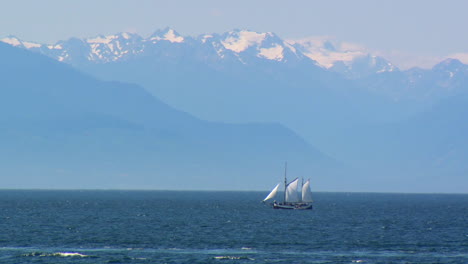 Sail-boat-in-Victoria,-BC-deploys-a-dinghy-with-Olympic-Mountains-in-the-background