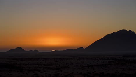 Beautiful-Summer-Sun-Setting-With-Warm-Colors-Sky-Behind-Silhouetted-Mountain-Of-Spitzkoppe-In-Namibia